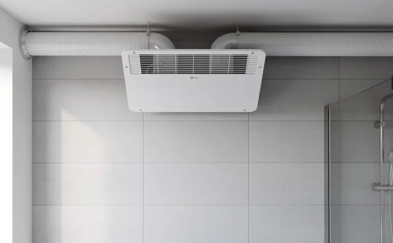 Mur de salle de bain moderne avec une VMC hygroréglable installée et des gaines apparentes sous une lumière naturelle douce.