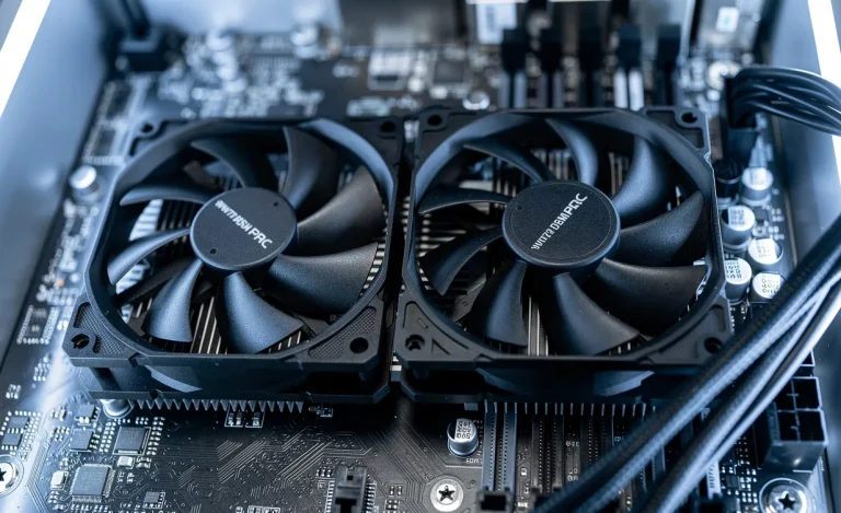 Gros plan sur un ventilateur PWM et un ventilateur DC posés côte à côte sur une carte mère éclairée par des LED bleues et blanches.