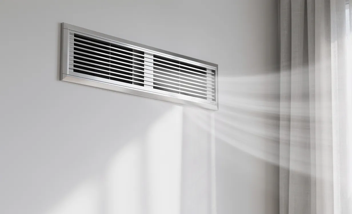 Un système de ventilation moderne fixé à un mur intérieur diffuse de l’air frais par une bouche d’aération.
