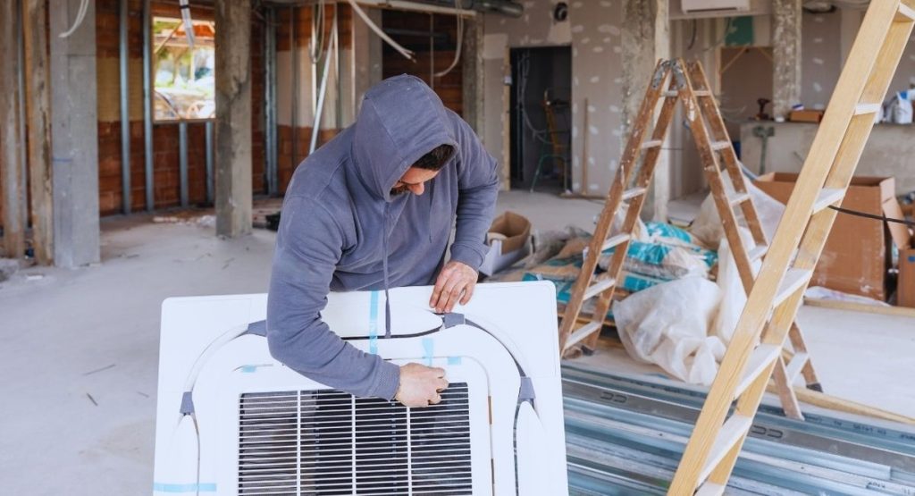 technicien installant une grille de ventilation VMC au plafond