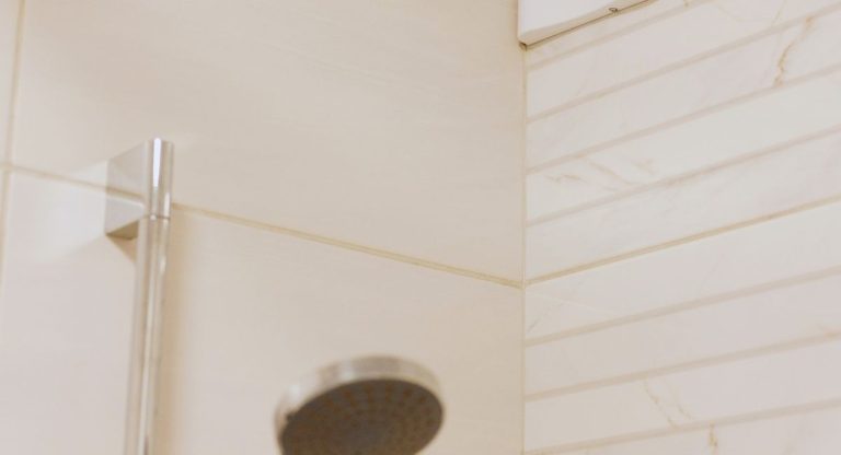 Angle d'une salle de bain avec douche et bouche de ventilation au plafond