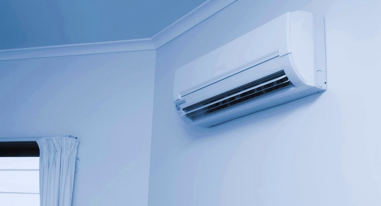 Climatiseur split mural blanc installé en hauteur dans une pièce