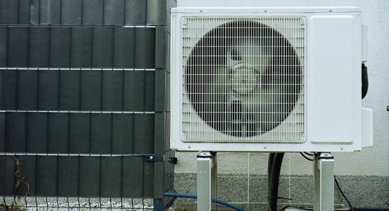 Unité extérieure de climatisation posée sur pieds contre un mur