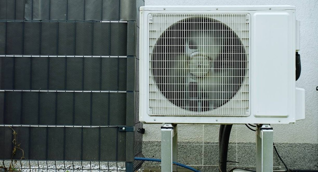 Unité extérieure de climatisation posée sur pieds contre un mur