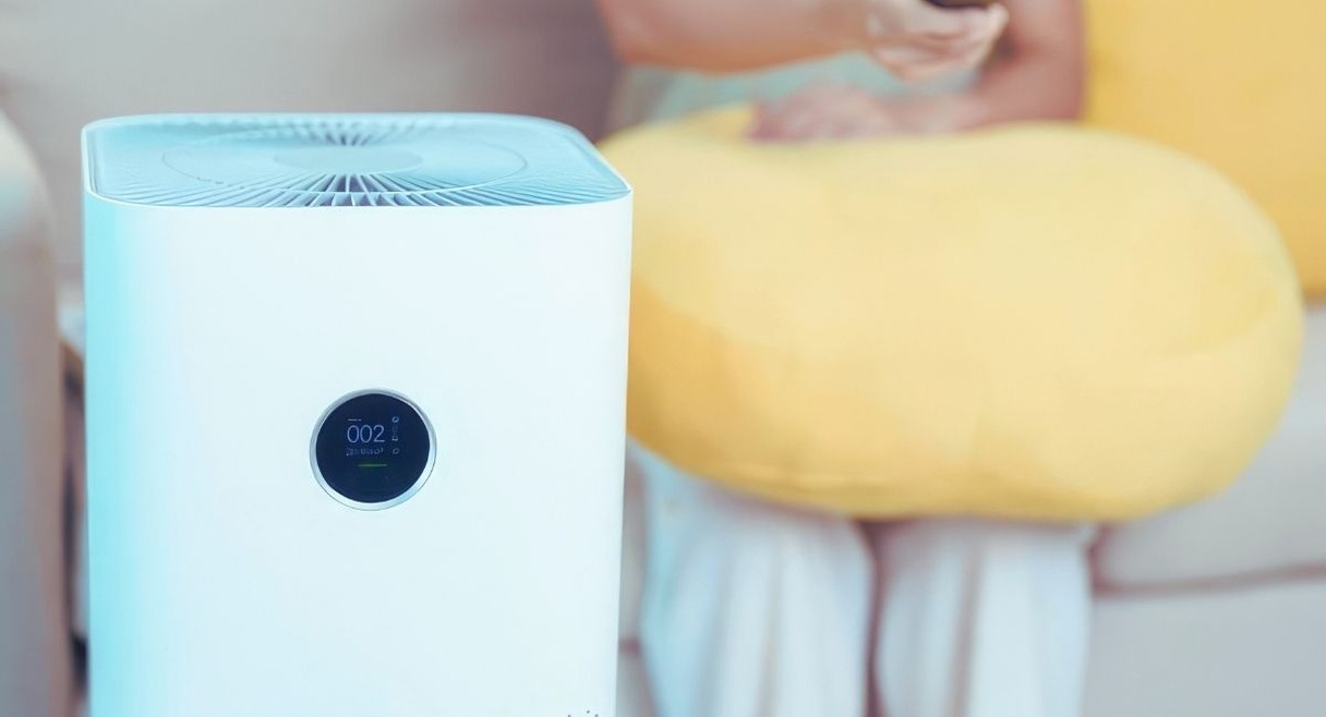 Purificateur d'air posé au sol dans un salon avec écran de qualité de l'air