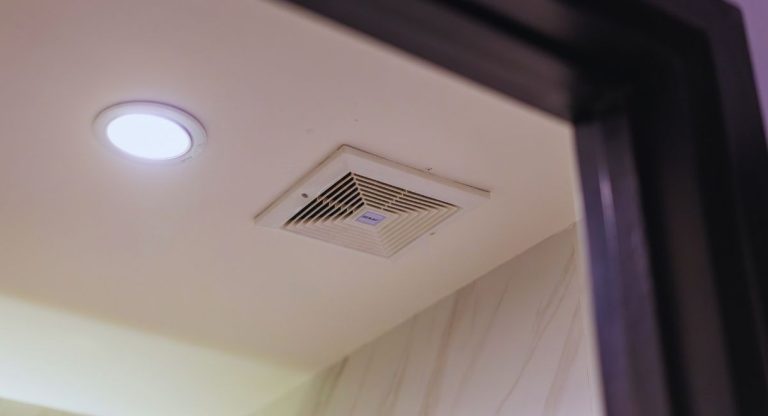 Grille d'extraction d'air au plafond d'une salle de bain avec spot lumineux